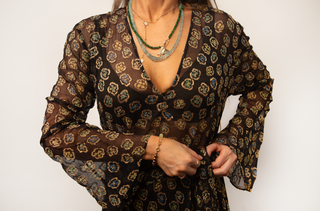 Woman wearing a black patterned dress with long sleeves on a white background