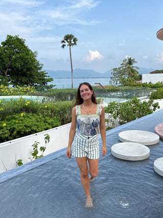 Woman standing on a rooftop with a scenic view of trees and water in the background