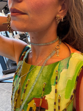 Close-up of a person wearing multiple necklaces and earrings with a colorful garment.