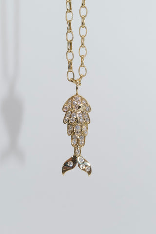 Gold necklace with a mermaid shaped pendant on a light gray background