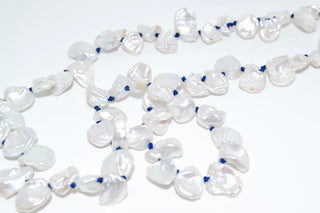 Necklace with white pearls and blue beads on a light gray background
