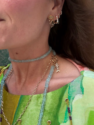 Close-up of a person wearing gold necklaces and earrings with a green top.