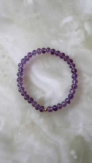 Amethyst stretch bracelet with a 14k gold bead, waterproof everyday design.