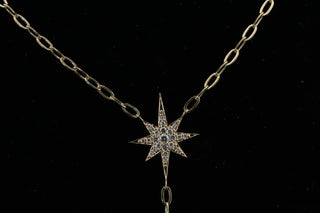 Celestial Moon Drop Necklace close-up, diamond starburst and crescent moon on a 9k gold oval rollo chain.