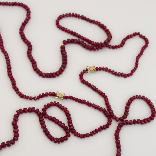 Faceted ruby wrap necklace on silk with 14k gold pave diamond bow details, no clasp.