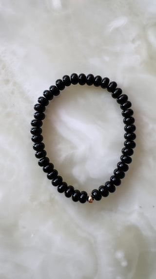 Onyx stretch bracelet with black onyx beads and a 14k gold bead.