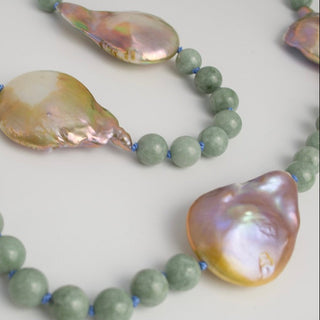 Necklace with large shell beads and green beads on a light background