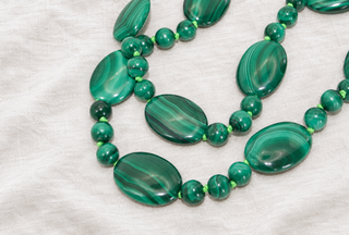 Close-up of the Ravello Malachite Necklace, graduated malachite beads on lime green thread with a 9k gold bolt ring clasp.