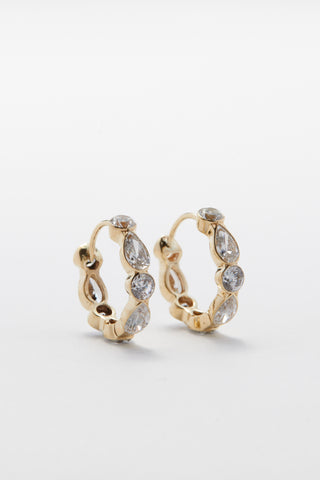 Gold hoop earrings with diamonds on a light gray background