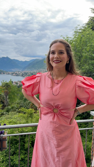 female founder in a pink dress standing outdoors with mountains and trees in the background