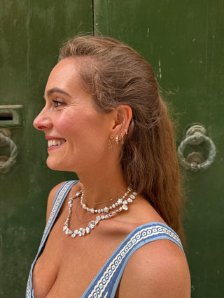 Woman wearing a blue and white dress with jewelry in front of a green door.